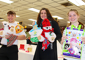 three students with stuffed animals and gifts